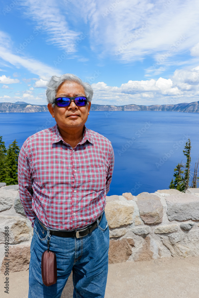 A retired Asian man happy and enjoy a holiday trip to celebrate the United States Independence Day at Crater Lake, Oregon National Park.