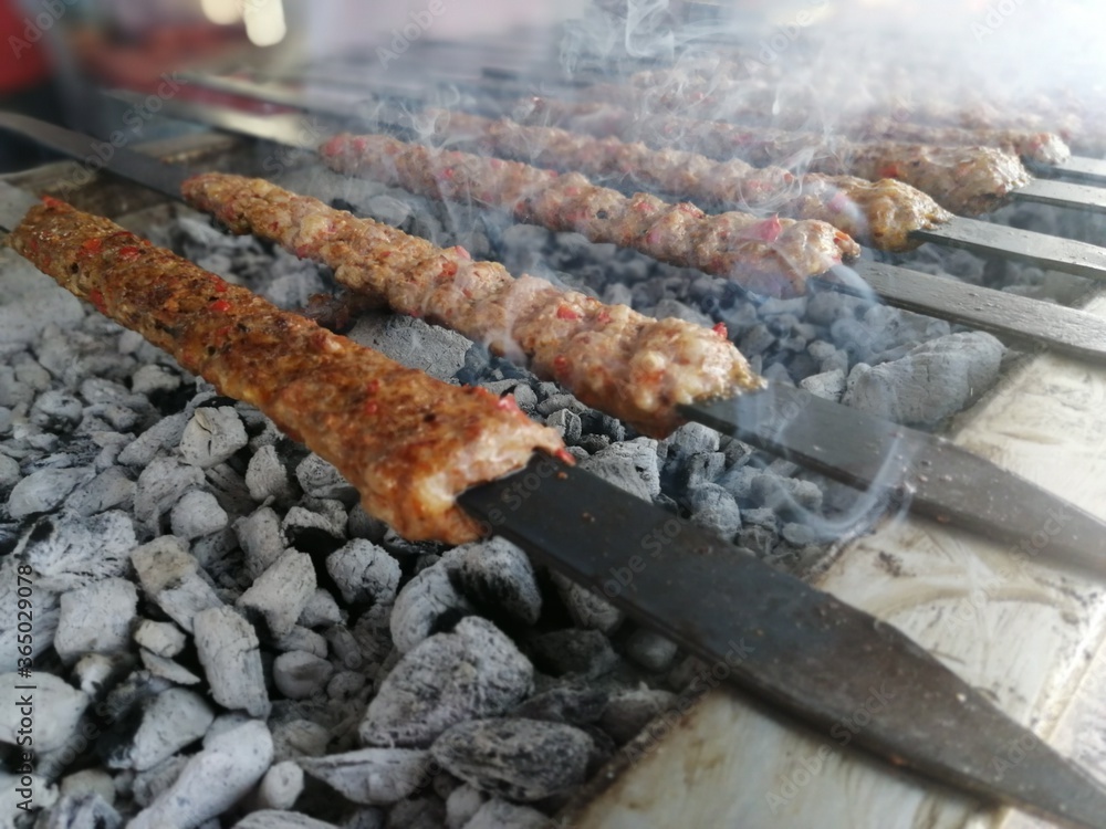 Cooking Adana kebabs on the restaurant style grill