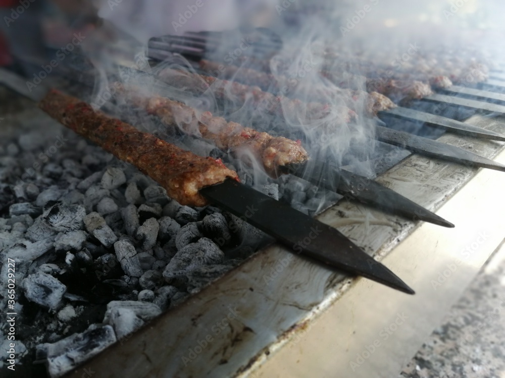 Cooking Adana kebabs on the restaurant style grill
