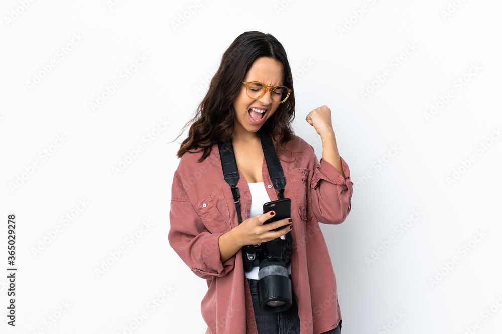 Young photographer woman over isolated white background with phone in victory position Young photographer woman over isolated white background with phone in victory position