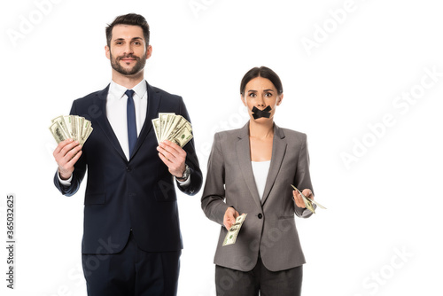 happy businessman holding dollars near businesswoman with duct tape on mouth isolated on white, gender inequality concept