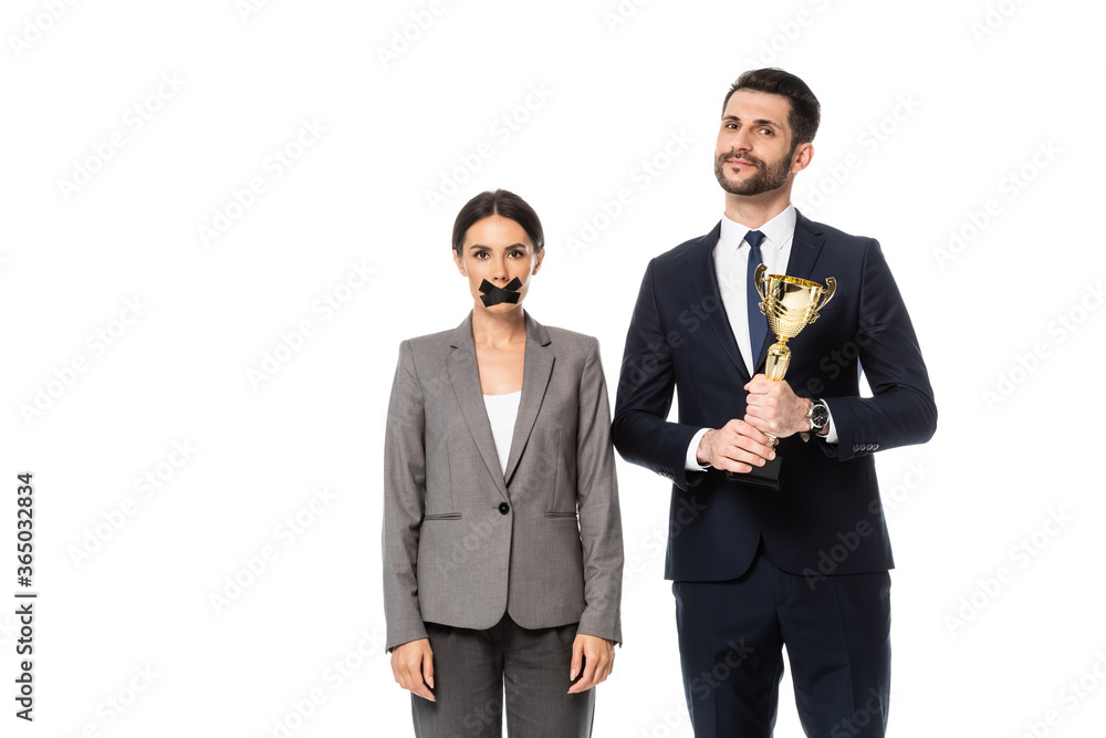 Φωτογραφία businessman holding trophy near businesswoman with duct tape on mouth isolated o