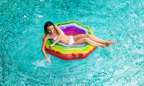 Top view photo of enjoying suntan excited woman in bikini on the inflatable mattress in the swimming pool. Summer Vacation. Relaxing in the Hotel pool