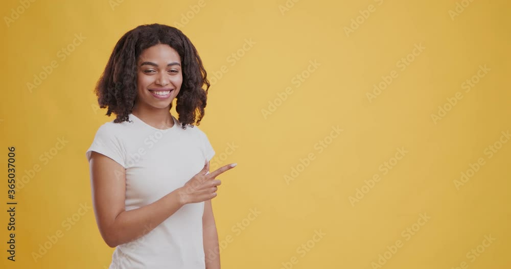 Joyful black girl pointing aside at copy space and smiling Joyful black girl pointing aside at copy space and smiling