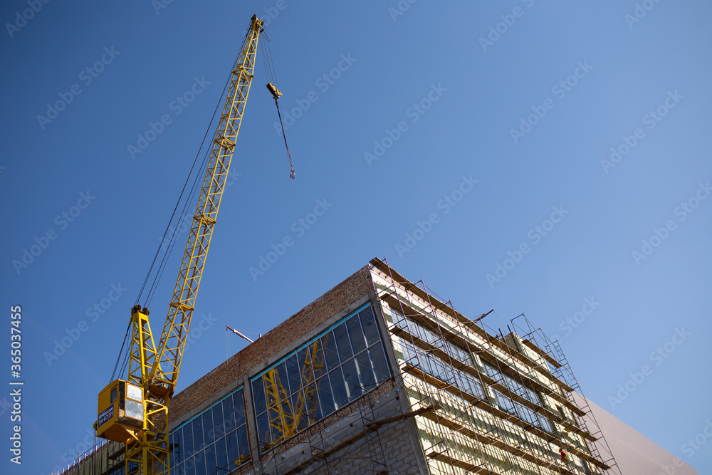 Building with construction crane and scaffolding blue sky.