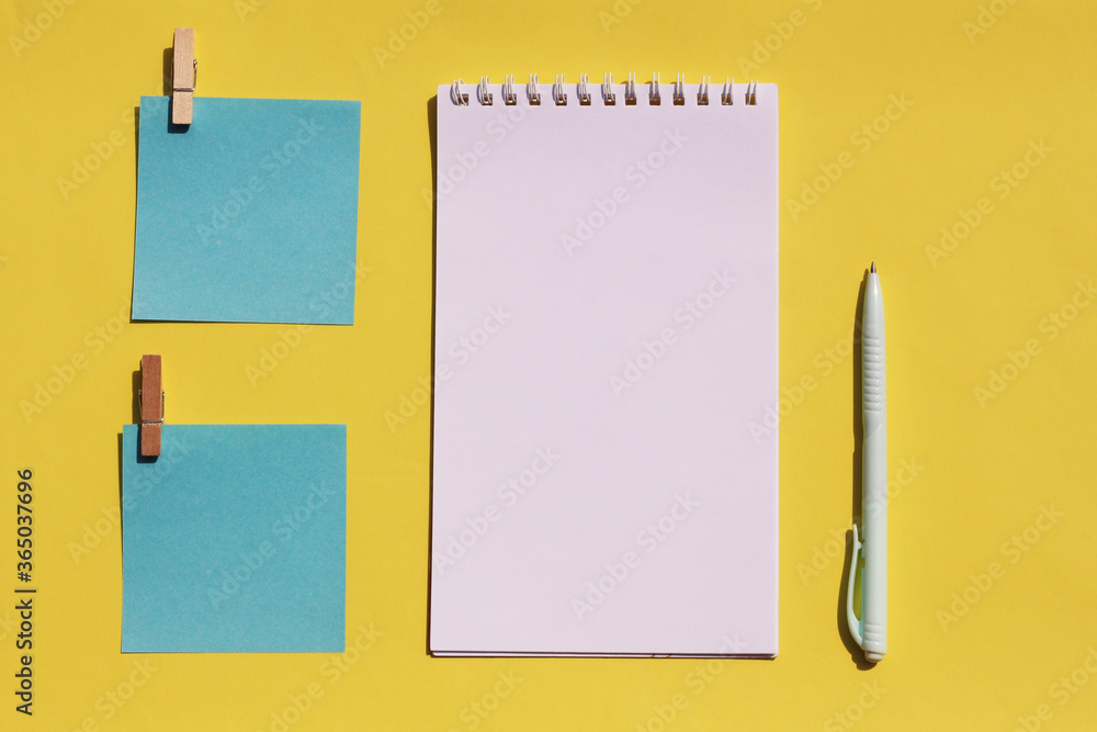 Flat lay leaflets for writing, a blank notebook on a spiral and a pen on a yellow background. Place for an inscription, top view Flat lay leaflets for writing, a blank notebook on a spiral and a pen on a yellow background. Place for an inscription, top view
