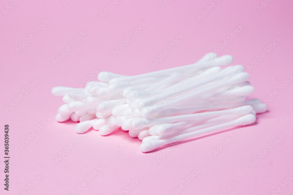Cotton buds on a pink background. A bunch of cotton buds lie on top of each other Cotton buds on a pink background. A bunch of cotton buds lie on top of each other