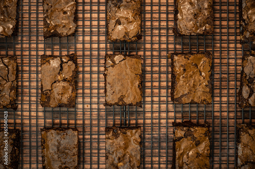 Overhead view of freshly baked brownies laid out on cooling rack in regular order.