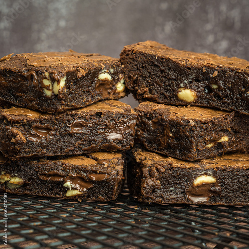 Close up side view of stacked fudge chocolate brownies with white chocolate chips on cooling rack.