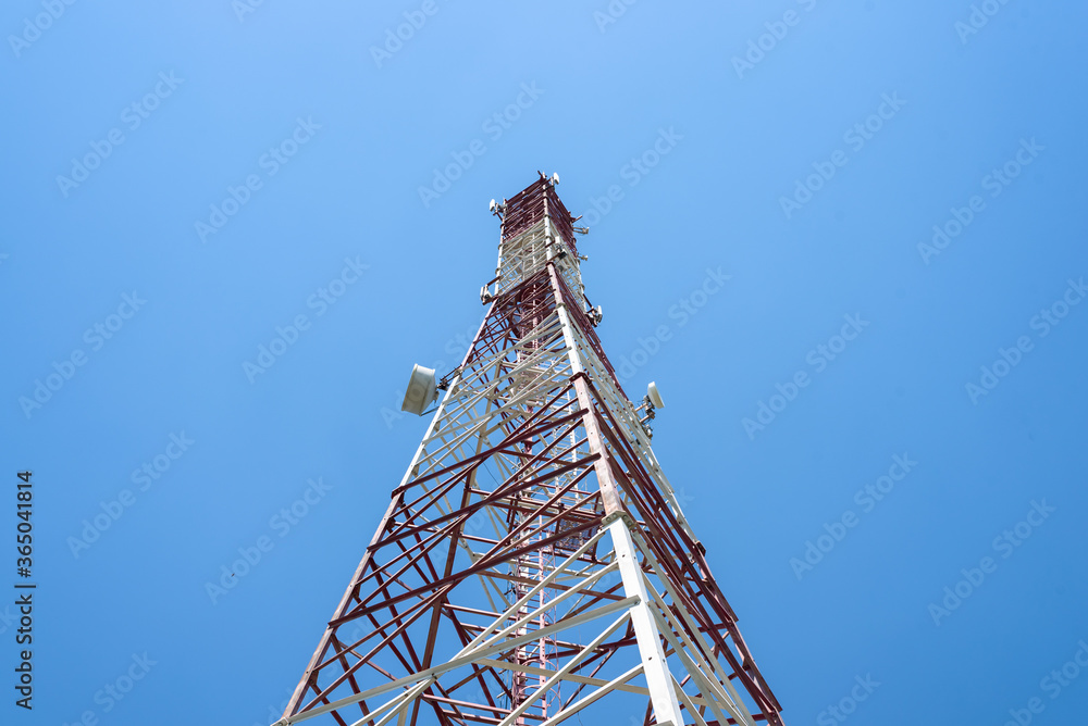 Cell tower with antennas on a blue sky background.