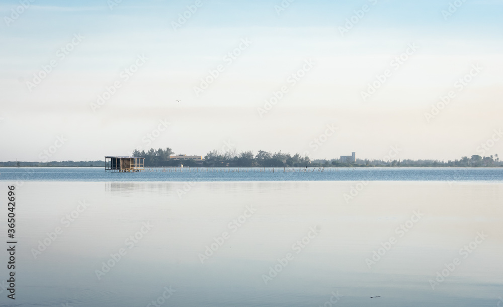 beautiful calm lake landscape at sunset with tilt house on the background