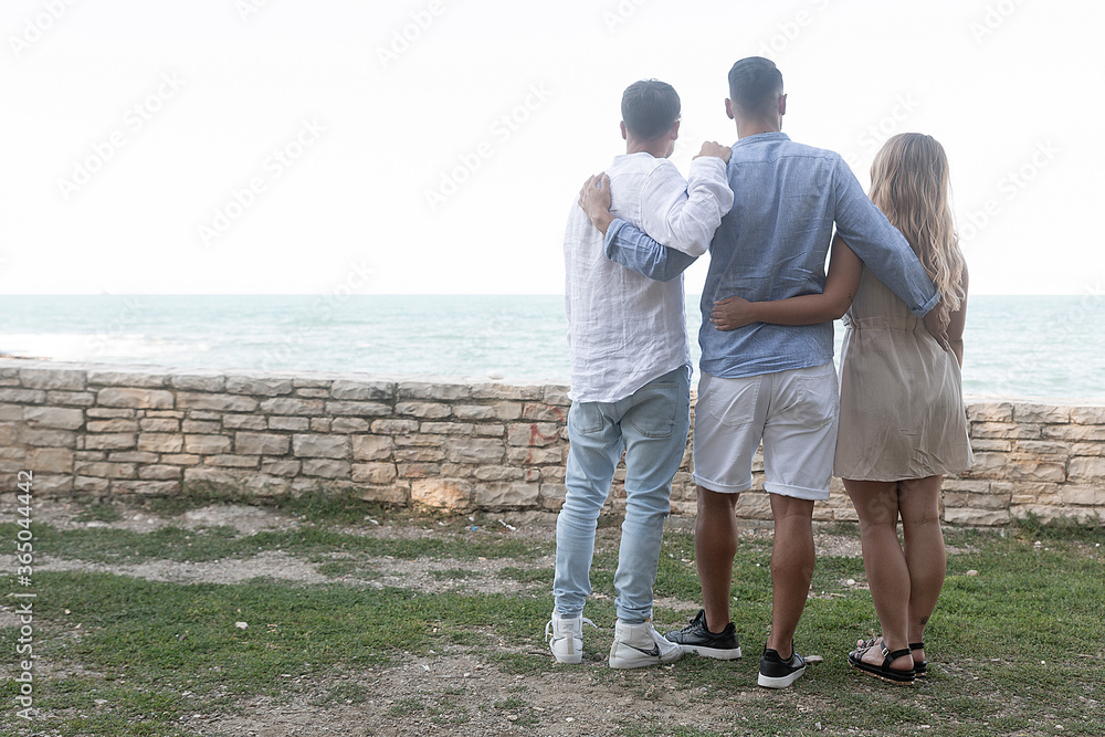 A italian woman an boy and a man are in a romantic scene with happy spouses in a loving embrace as they look at the horizon almost at sunset A italian woman an boy and a man are in a romantic scene with happy spouses in a loving embrace as they look at the horizon almost at sunset