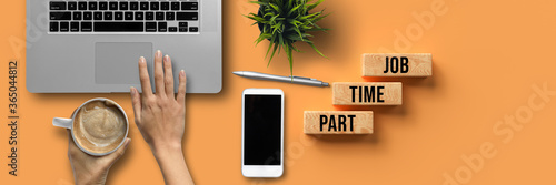 hand over a computer with coffee and office equipment and message PART TIME JOB on orange background