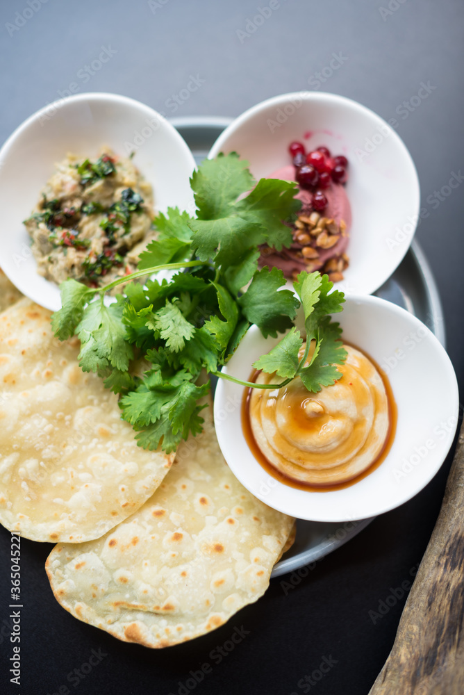 Assorted Hummus Dips with Flatbread and Fresh Coriander Leaves