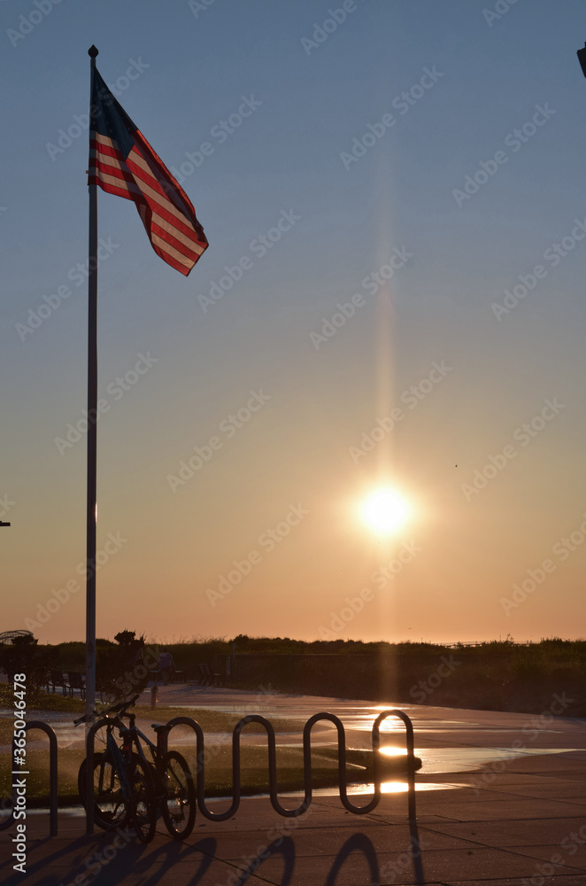Fototapeta premium American Flag at Sunrise over Atlantic Ocean