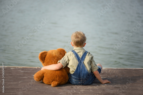 A little boy hugs a teddy bear. Back view. photo