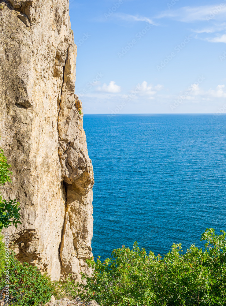 Rocky seaside against blue summer sea. Concept of hiking and traveling. Solo outdoor activities. Copy space, natural background