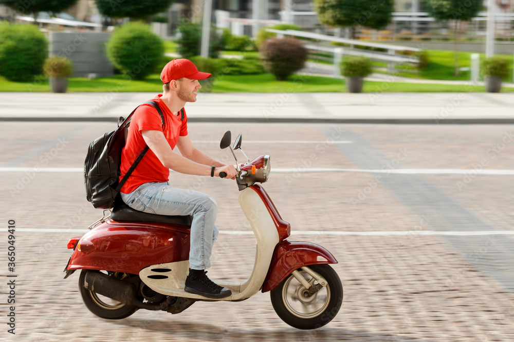 Young guy working as deliveryman. Man is driving a scooter