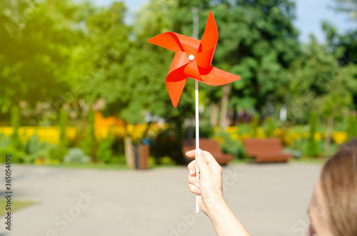 Female hand holding windmill on park background