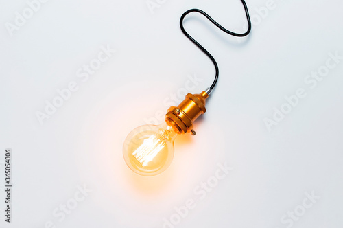 Creative idea concept, designer lamp, modern interior item. Vintage fashionable edison lamp on light gray background. Top view flat lay copy space. Lighting, electricity, background with lamp