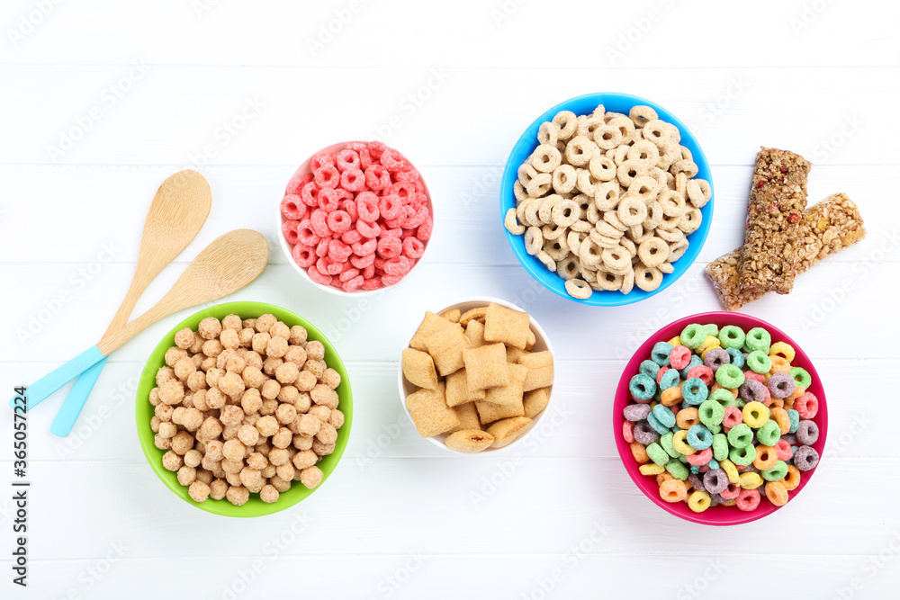 Various corn flakes in bowls with granola bars on white wooden table Various corn flakes in bowls with granola bars on white wooden table