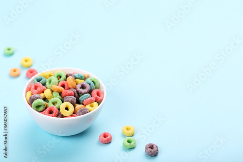 Colorful corn rings in bowl on blue background