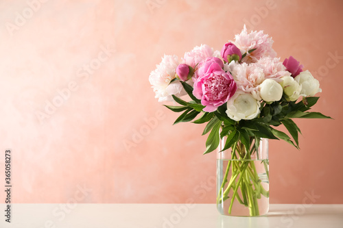 Beautiful peony bouquet in vase on table against pink background. Space for text