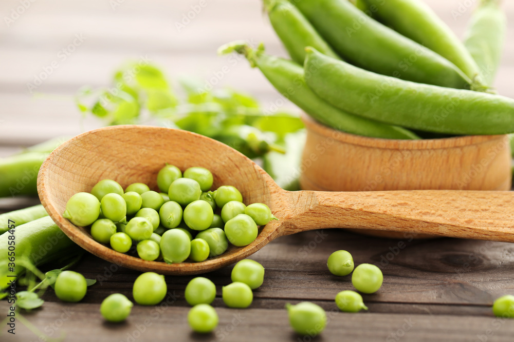 Fresh peas in spoon on brown wooden table Fresh peas in spoon on brown wooden table