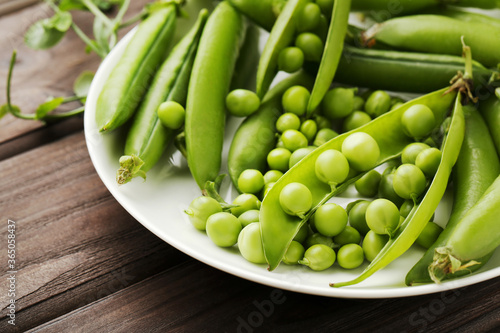 Wallpaper Mural Green pea pods in plate on brown wooden table Torontodigital.ca