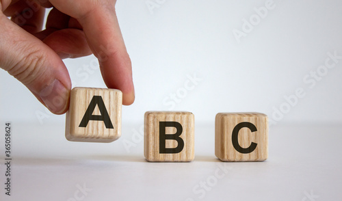 Hand making a choice between cubes with leteres A, B and C on beautiful white background. Business concept. Copy space.