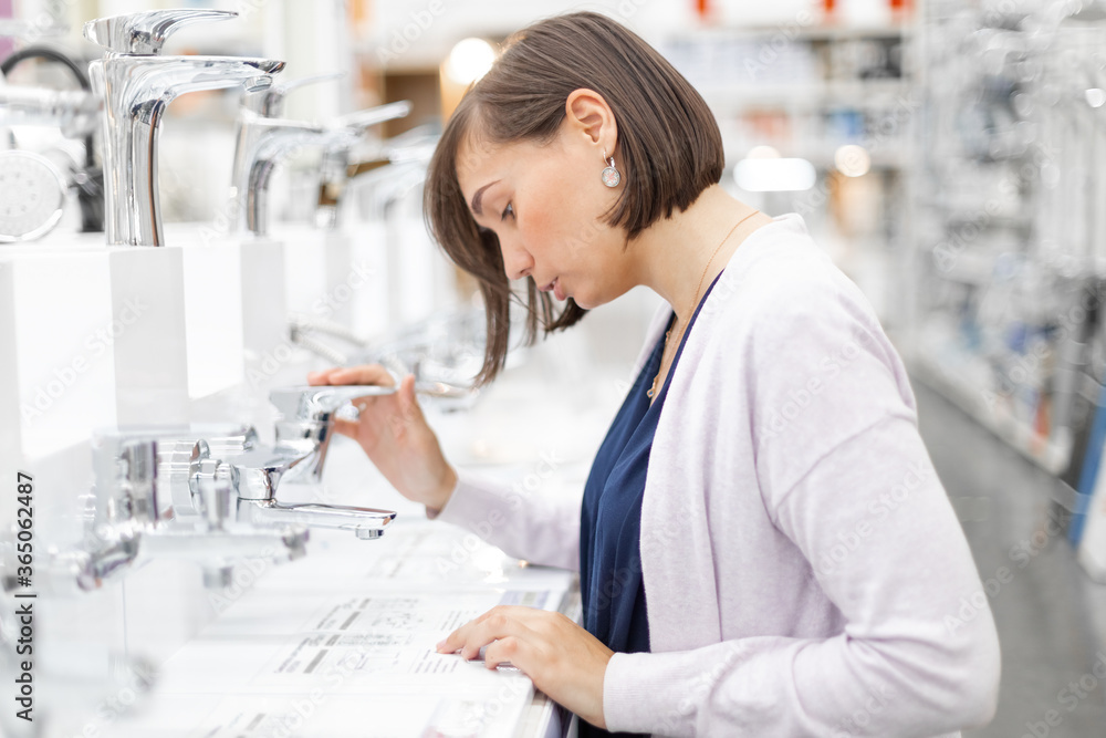 Pretty young woman choosing a bathroom/kitchen tap in a home furnishings retail store Pretty young woman choosing a bathroom/kitchen tap in a home furnishings retail store