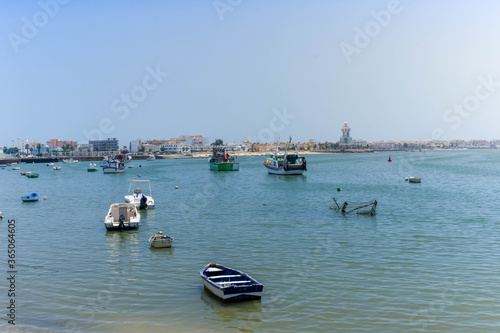 View of Isla Cristina from the port with fishing boats and the lighthouse in the background on a clear and sunny day. Isla Cristina, Huelva, Andalusia, Spain