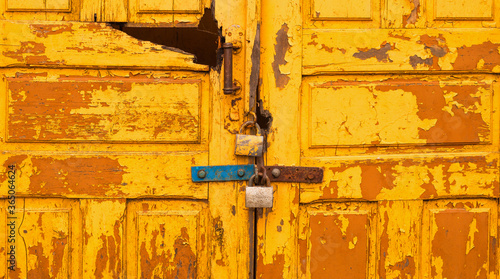 the old yellow door is closed with a padlock