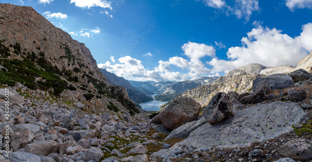 A panoramic shot of Upper Golden Lake, Lake Louise and Golden Lake. A group of three backpackers is seen hiking north on the Hay Pass Trail.