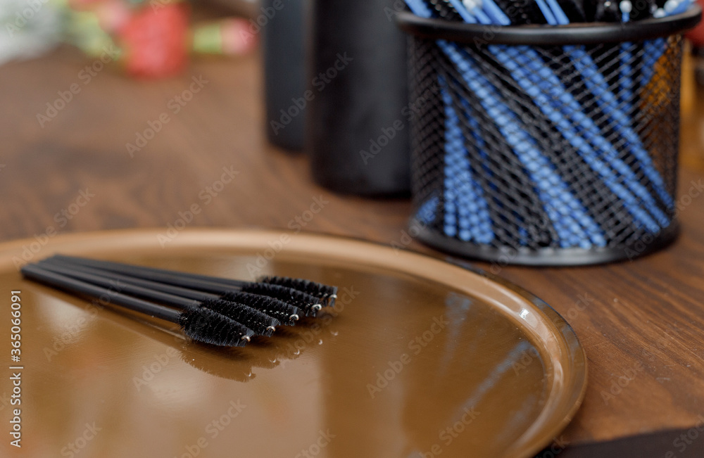 Eyebrow brushes. Black eyebrow brushes on the table. Cosmetic devices for eyebrow correction on the table. Flowers out of focus on the table Eyebrow brushes. Black eyebrow brushes on the table. Cosmetic devices for eyebrow correction on the table. Flowers out of focus on the table