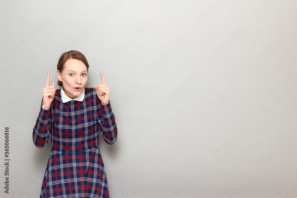 Amazed surprised girl is pointing with fingers upwards at copy space Amazed surprised girl is pointing with fingers upwards at copy space