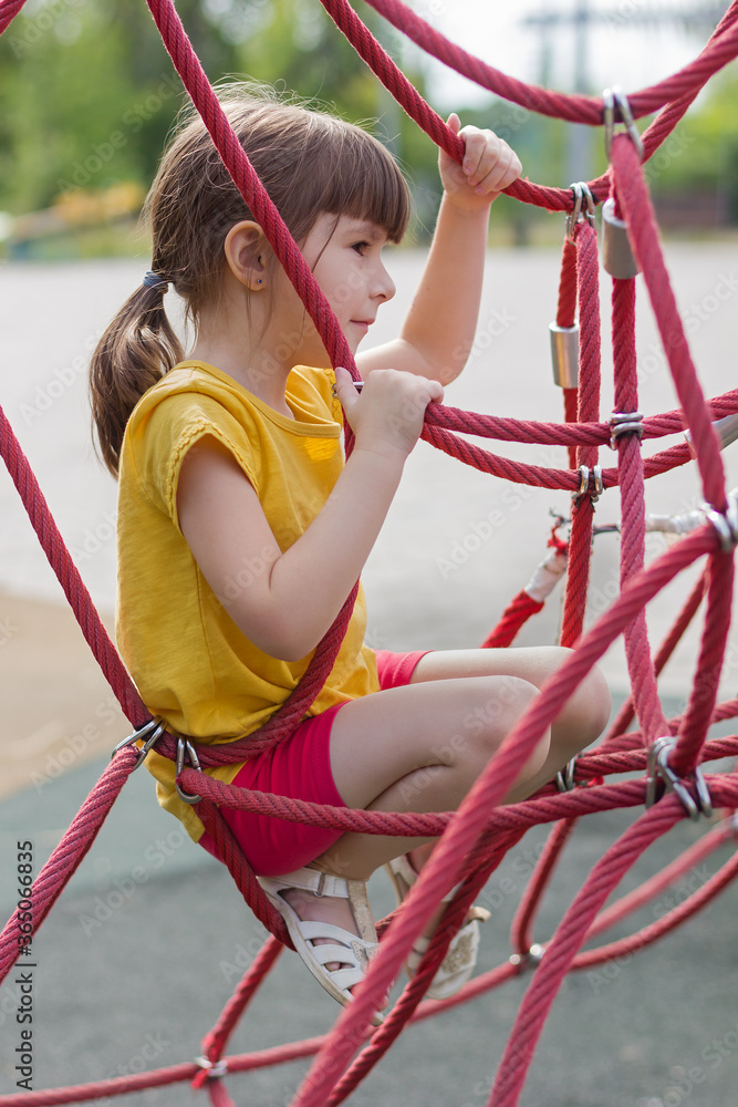 Adorable 6 years old girl climbing the net in the playground Adorable 6 years old girl climbing the net in the playground