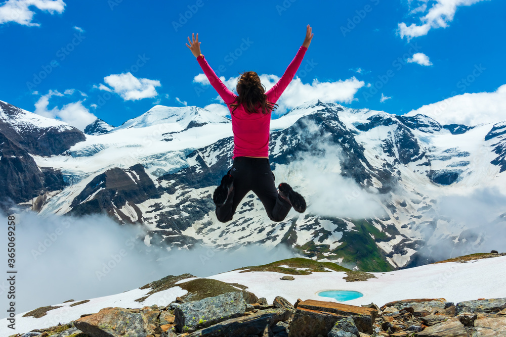 woman happily jumping after reaching the top of the mountain in the Austrian alps 