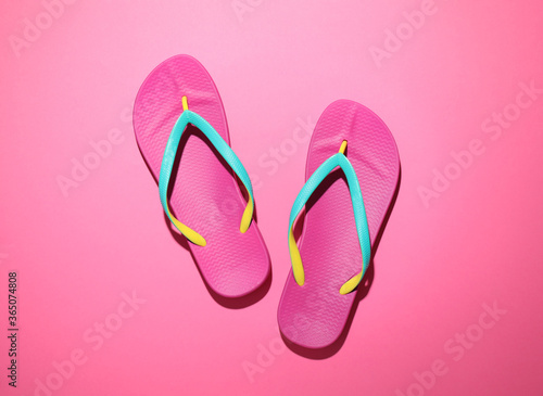 Pair of stylish flip flops on pink background, top view. Beach objects