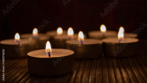 candles on a dark background. Close up and selective focus of tea light with blurred candles in the beackground