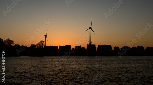 Silhouettes of houses, windmills and trees in last evening light after sunset, along canal Ghent - Terneuzen in the harbor of Ghent 