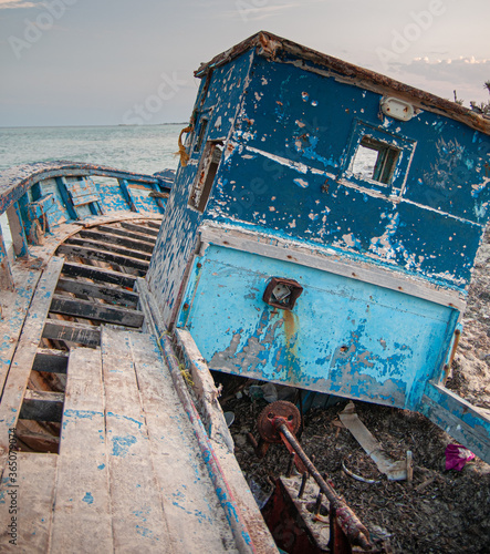 Old wrecked boat on the beach with the ropes hanging on