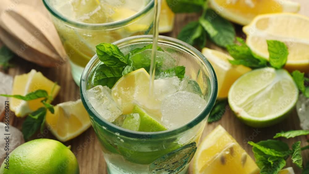 Pouring soda water into glasses filled with ice and citrus fruits. Refreshing summer drink
Pouring soda water into glasses filled with ice and citrus fruits. Refreshing summer drink