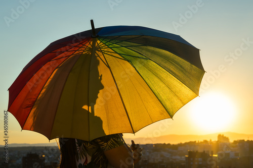 Silhouette of a girl under an umbrella in lgtbi colors.