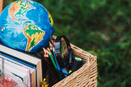 Back to school - school equipment, books and globe with ukrainian signature in the basket. Soft focus. Place for text