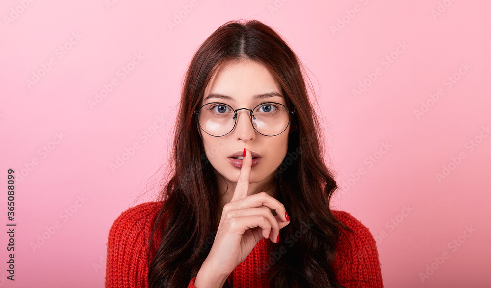 Portrait of a stylish long-haired brunette lady in a red sweater and glasses on a pink background. Portrait of a stylish long-haired brunette lady in a red sweater and glasses on a pink background.