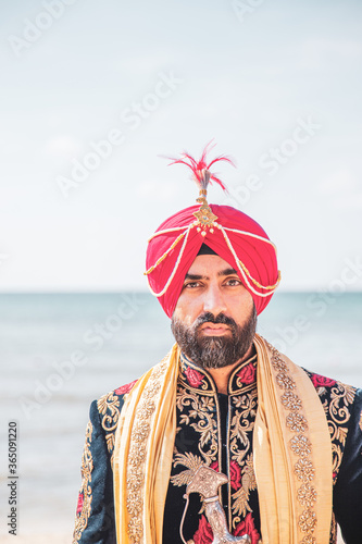 Attractive Sikh man wearing traditional wedding clothing with ceremonial sword