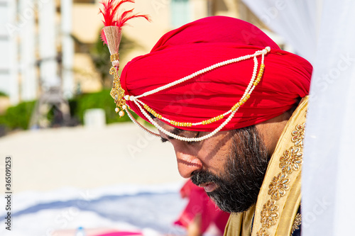 Attractive Sikh man wearing traditional wedding clothing with ceremonial sword
