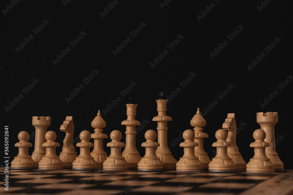 White chess stands in a row on a chessboard on a black background.Copy space for text
