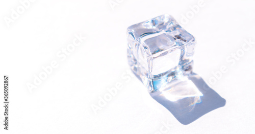 Transparent cube-shaped crystal in light rays on a white background.Creative background,abstract texture,copy space.Selective focus with shallow depth of field